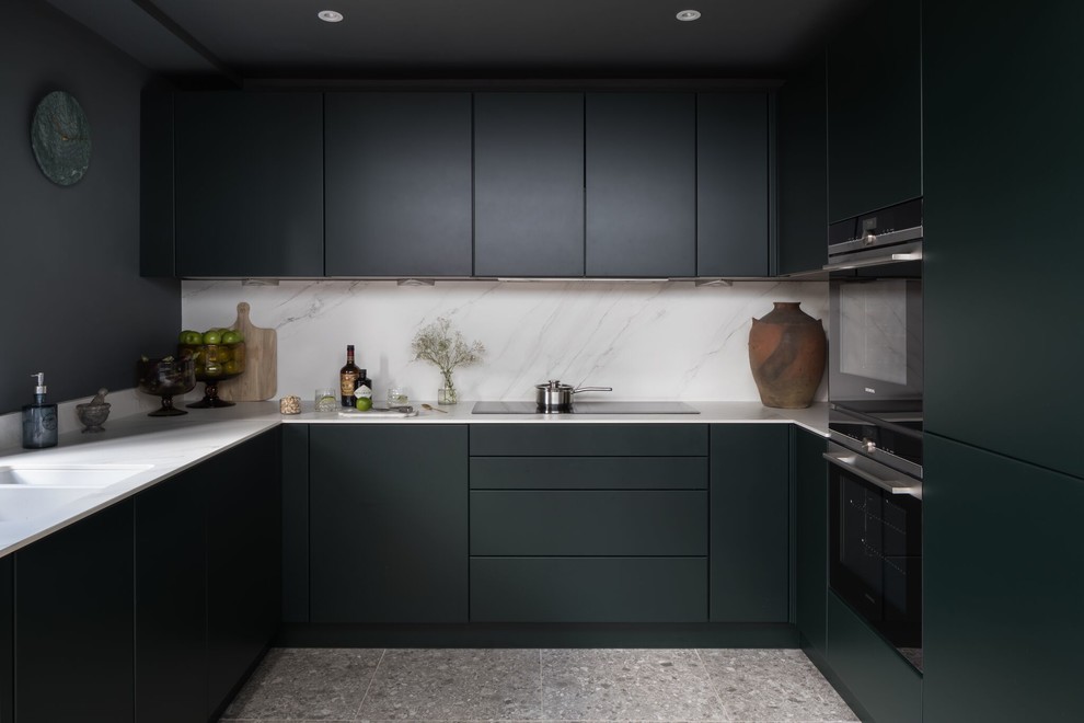This is an example of a small contemporary u-shaped separate kitchen in London with an integrated sink, flat-panel cabinets, green cabinets, white splashback, porcelain splashback, panelled appliances, ceramic floors, no island and grey floor.