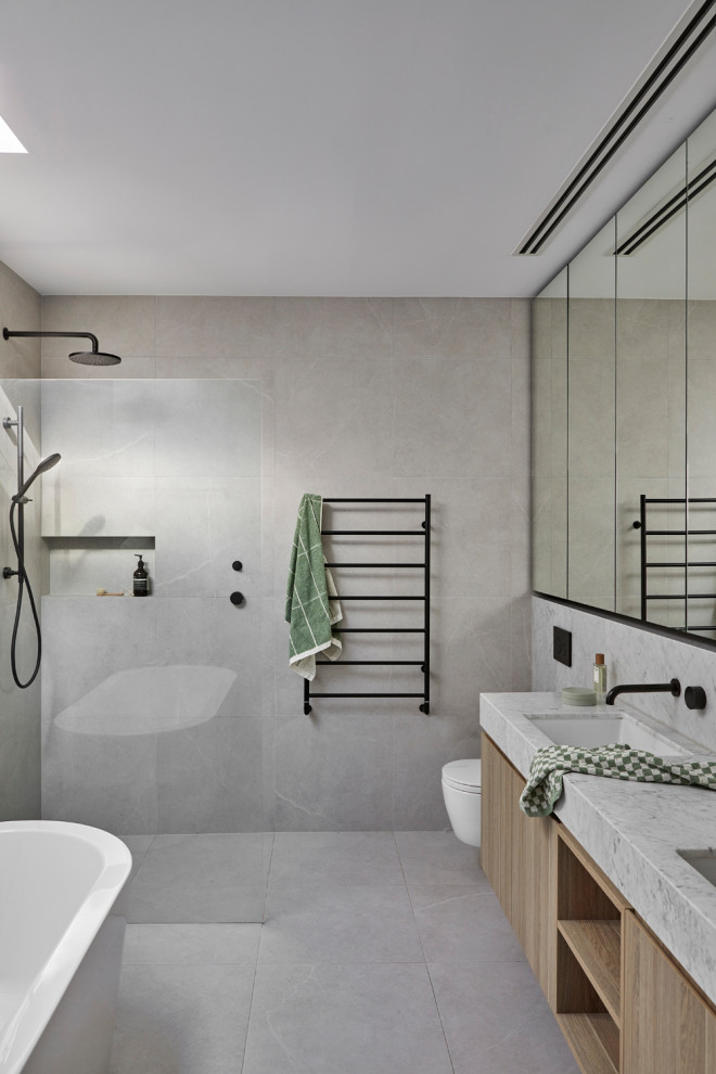 Photo of a medium sized contemporary ensuite bathroom in Melbourne with marble worktops, grey floors, white worktops, a built in vanity unit, a freestanding bath, a built-in shower, a wall mounted toilet, grey tiles, stone tiles, grey walls, a submerged sink, an open shower and double sinks.