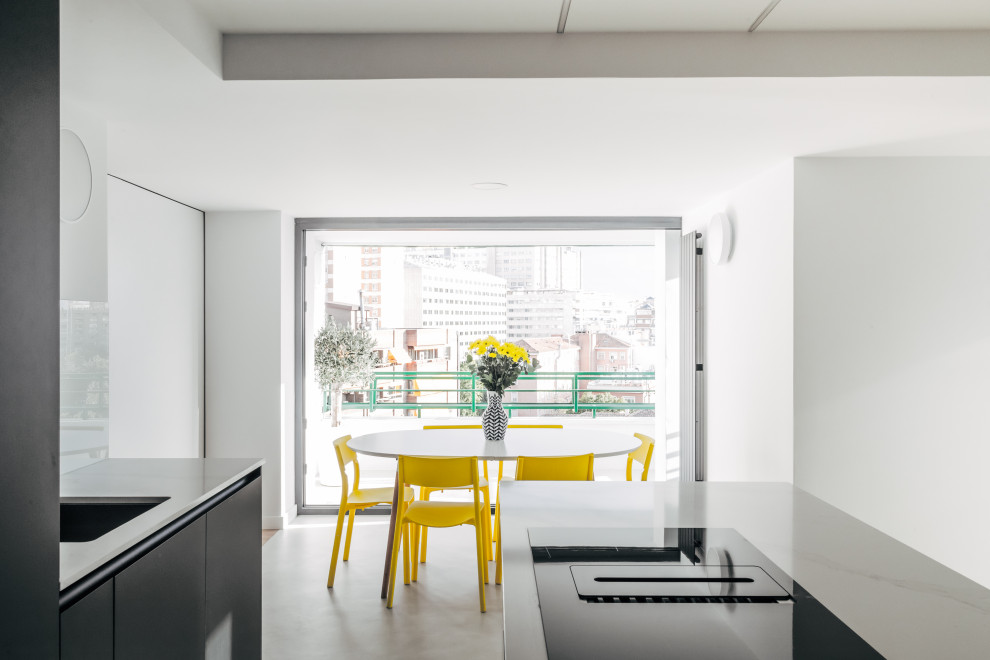 Modelo de comedor de cocina actual pequeño sin chimenea con paredes blancas, suelo de cemento y suelo gris
