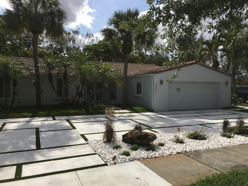 This is an example of a mid-sized contemporary front yard partial sun driveway in Miami with concrete pavers.