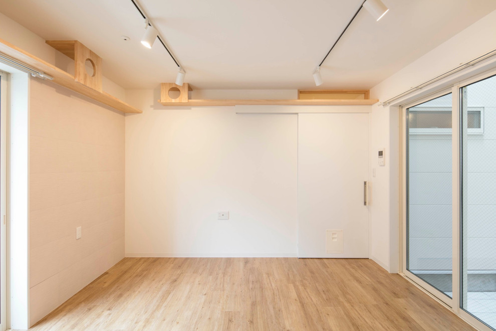 Photo of a mid-sized scandinavian gender-neutral kids' playroom in Tokyo with white walls, light hardwood floors, beige floor, wallpaper and brick walls.