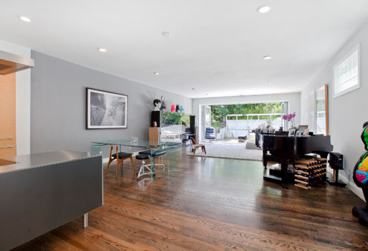 Mid-sized contemporary l-shaped open plan kitchen in San Francisco with flat-panel cabinets, grey cabinets, stainless steel benchtops, stainless steel appliances, dark hardwood floors, with island and brown floor.