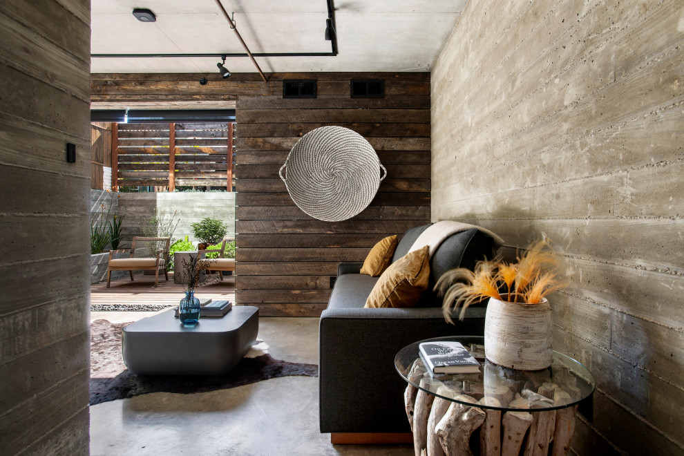 На фото: рабочее место среднего размера в стиле лофт с коричневыми стенами, бетонным полом, серым полом, деревянными стенами и отдельно стоящим рабочим столом