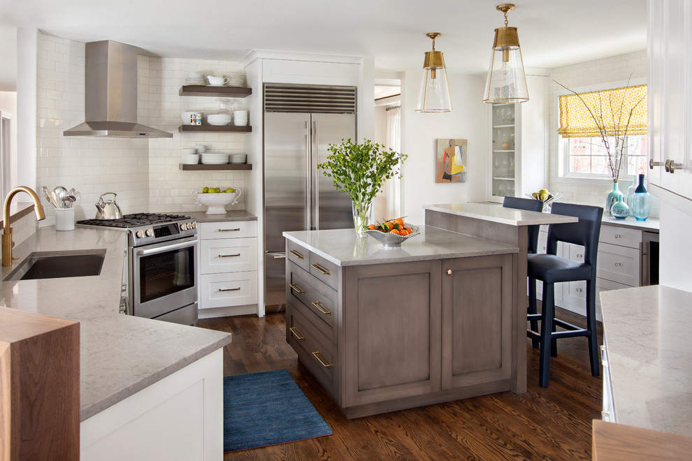 This is an example of a large transitional kitchen in Denver with an undermount sink, shaker cabinets, stainless steel cabinets, quartzite benchtops, white splashback, cement tile splashback, white appliances, medium hardwood floors, with island, brown floor and grey benchtop.