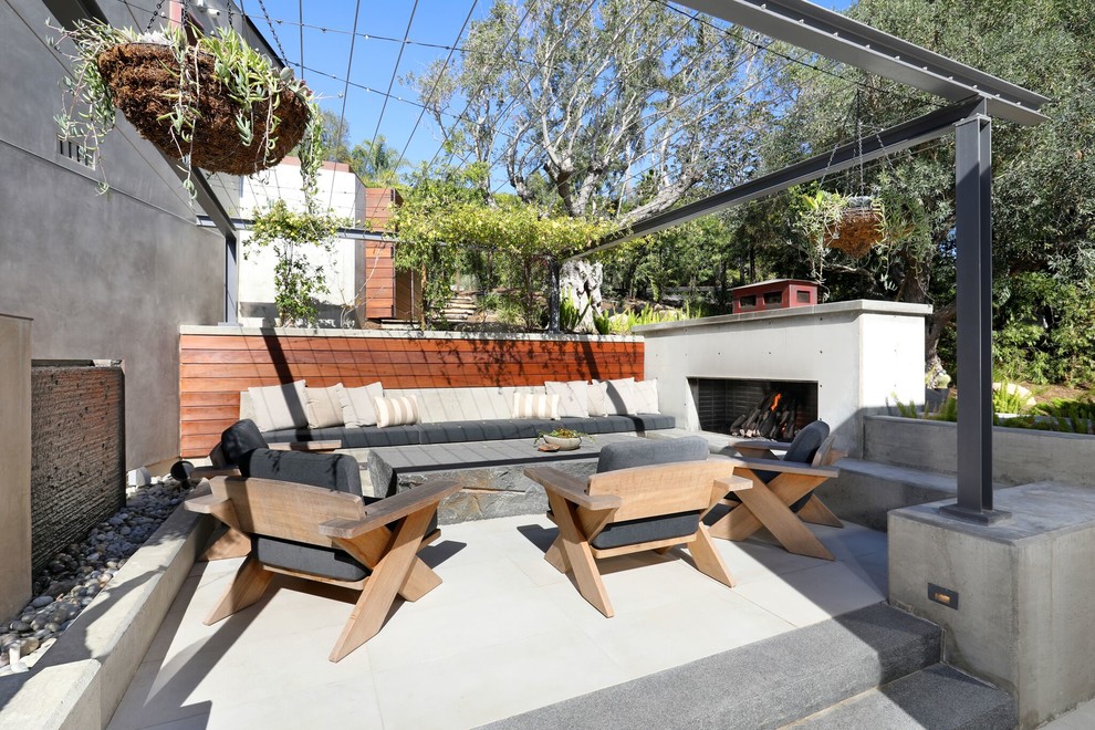 Example of a large trendy side yard concrete patio design in Orange County with a fireplace and a pergola