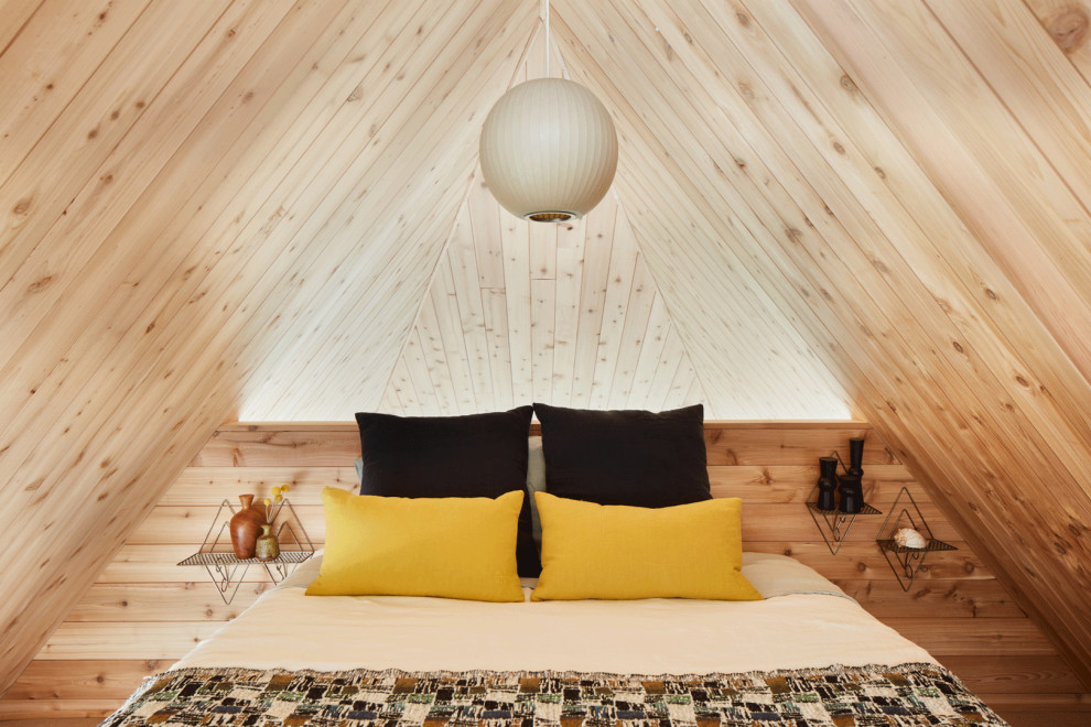 Inspiration for a small midcentury loft-style bedroom in New York with vaulted and wood walls.