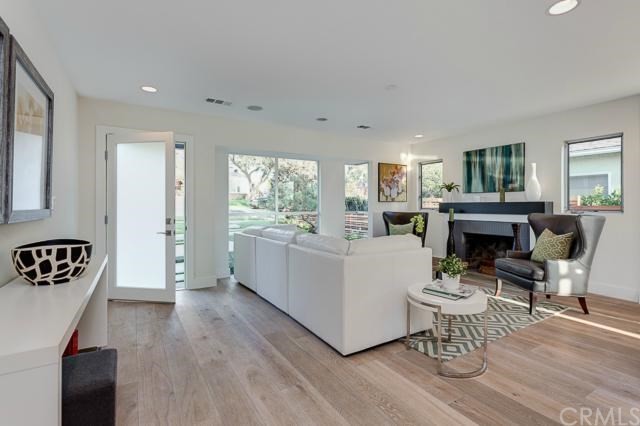 This is an example of a small modern open concept living room in Los Angeles with light hardwood floors, a standard fireplace, a wall-mounted tv, white walls and a tile fireplace surround.