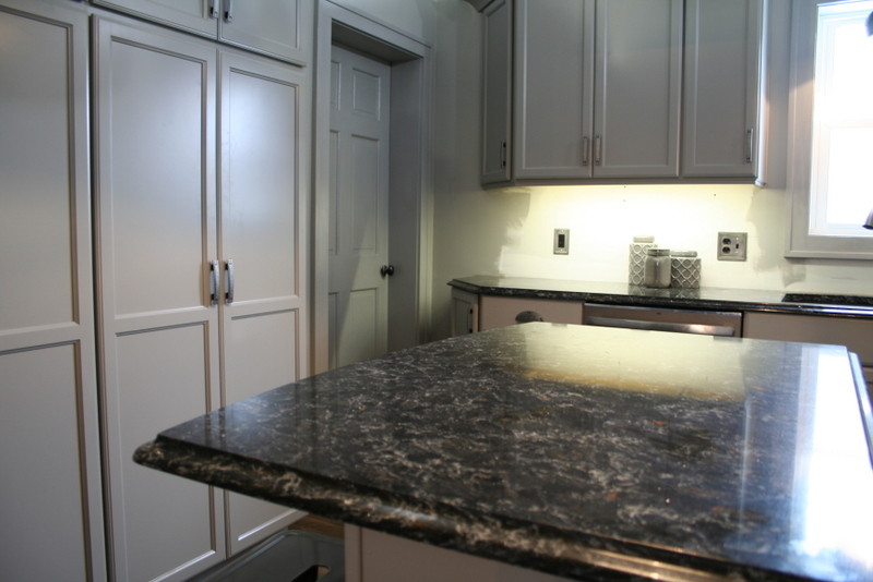 Example of a small transitional l-shaped vinyl floor enclosed kitchen design with a double-bowl sink, flat-panel cabinets, gray cabinets, quartz countertops, stainless steel appliances and an island