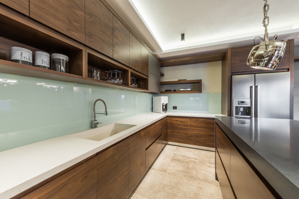 Photo of a mid-sized industrial u-shaped eat-in kitchen in Sydney with an integrated sink, flat-panel cabinets, green cabinets, quartz benchtops, green splashback, glass sheet splashback, stainless steel appliances, limestone floors and with island.