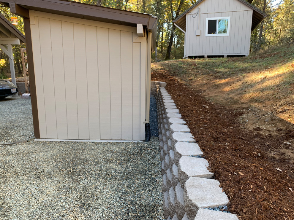 Mid-sized traditional sloped partial sun xeriscape in Sacramento with a retaining wall and gravel for summer.