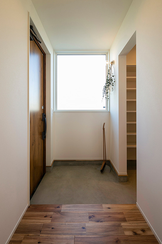 На фото: узкая прихожая среднего размера в скандинавском стиле с белыми стенами, паркетным полом среднего тона, одностворчатой входной дверью, входной дверью из дерева среднего тона, коричневым полом, потолком с обоями и обоями на стенах с