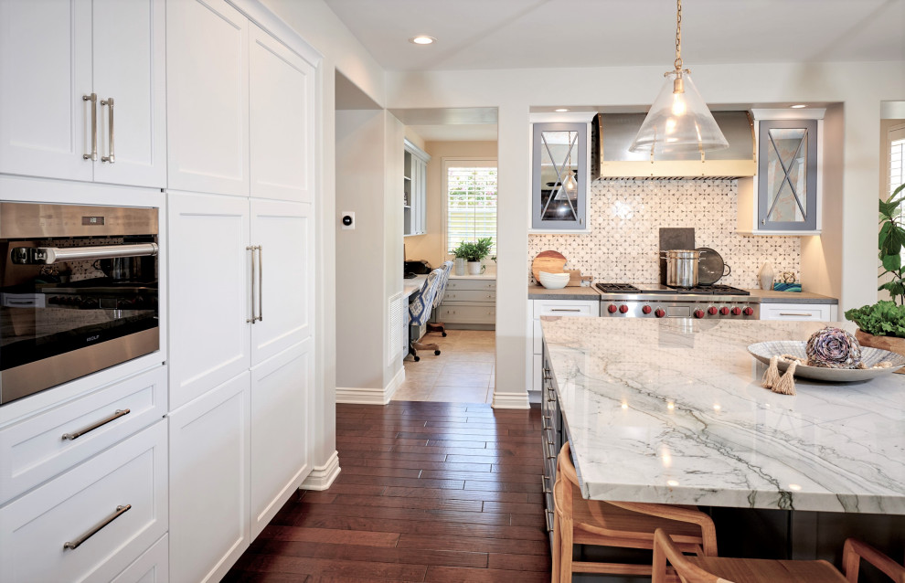 Large traditional u-shaped open plan kitchen in San Diego with an undermount sink, recessed-panel cabinets, white cabinets, quartzite benchtops, grey splashback, marble splashback, stainless steel appliances, dark hardwood floors, with island, brown floor and white benchtop.