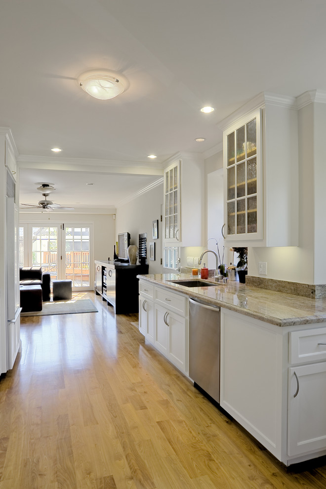 Photo of a mid-sized modern galley kitchen in San Francisco with marble benchtops, glass-front cabinets, white cabinets, light hardwood floors, no island, an undermount sink and yellow floor.