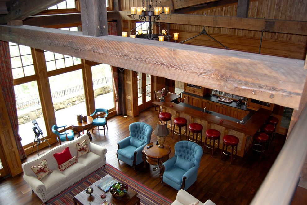 Photo of an expansive country open concept living room in Other with a home bar, beige walls, dark hardwood floors, a standard fireplace, a stone fireplace surround and a wall-mounted tv.