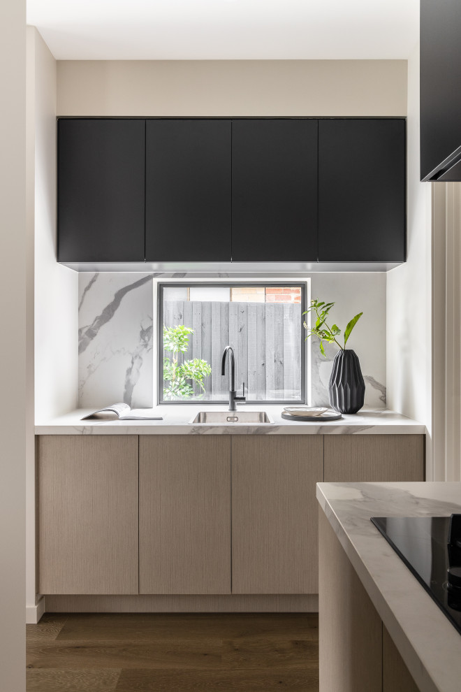 Moderne Küche mit Waschbecken, Quarzwerkstein-Arbeitsplatte, Küchenrückwand in Weiß, Rückwand aus Quarzwerkstein, braunem Holzboden, weißer Arbeitsplatte, flächenbündigen Schrankfronten und schwarzen Schränken in Melbourne