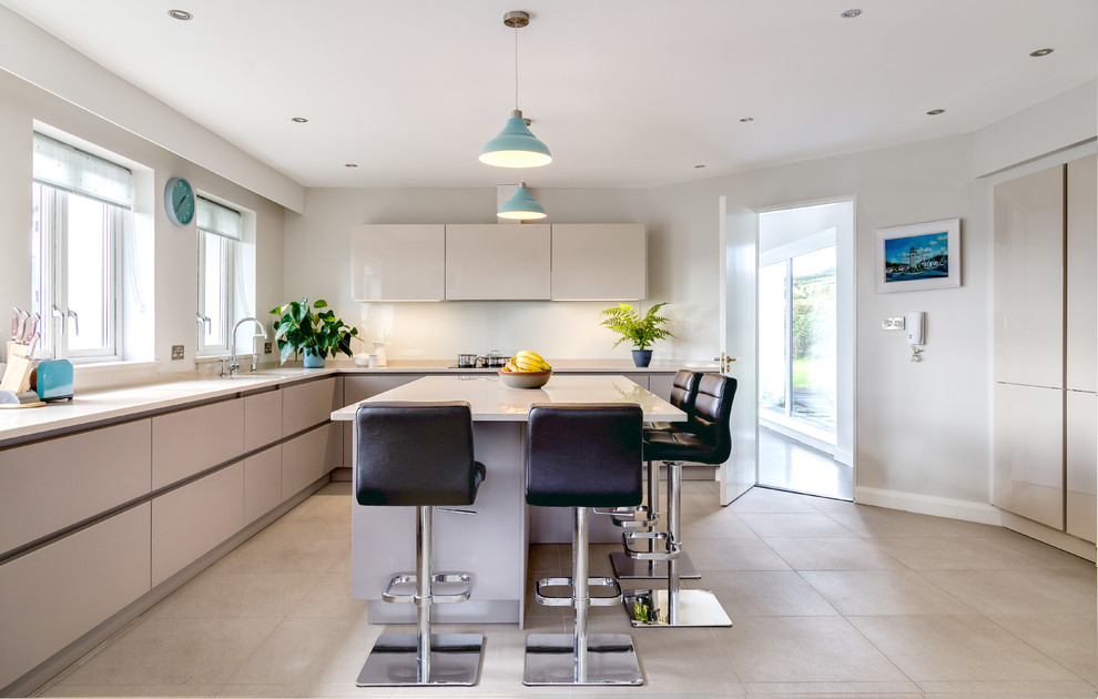 Large contemporary l-shaped kitchen in Dublin with flat-panel cabinets, quartzite benchtops, glass sheet splashback, panelled appliances, porcelain floors and with island.