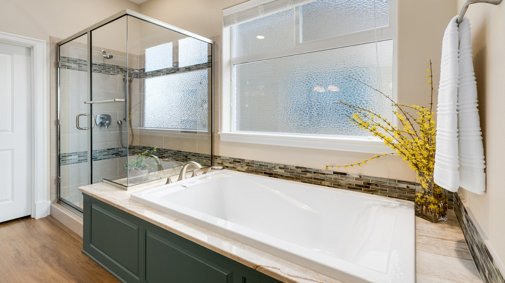 This is an example of a mid-sized traditional master bathroom in Other with raised-panel cabinets, green cabinets, a drop-in tub, beige tile, beige walls, an undermount sink, quartzite benchtops, brown floor, a hinged shower door, beige benchtops, an enclosed toilet, a double vanity and a built-in vanity.