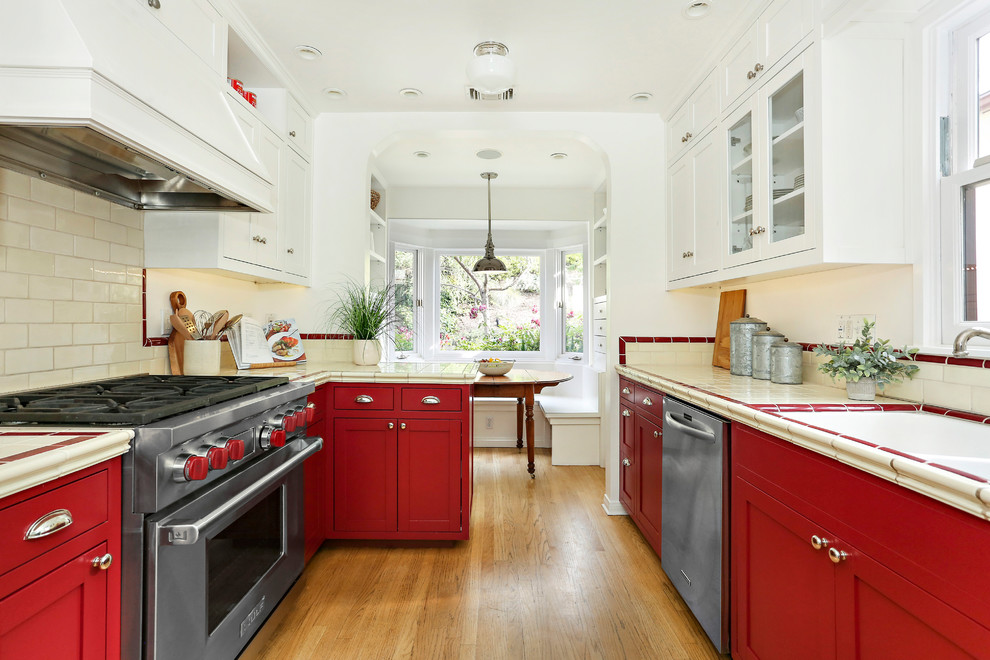 Transitional galley eat-in kitchen in Los Angeles with an undermount sink, shaker cabinets, red cabinets, beige splashback, subway tile splashback, stainless steel appliances, medium hardwood floors, no island, beige floor and multi-coloured benchtop.