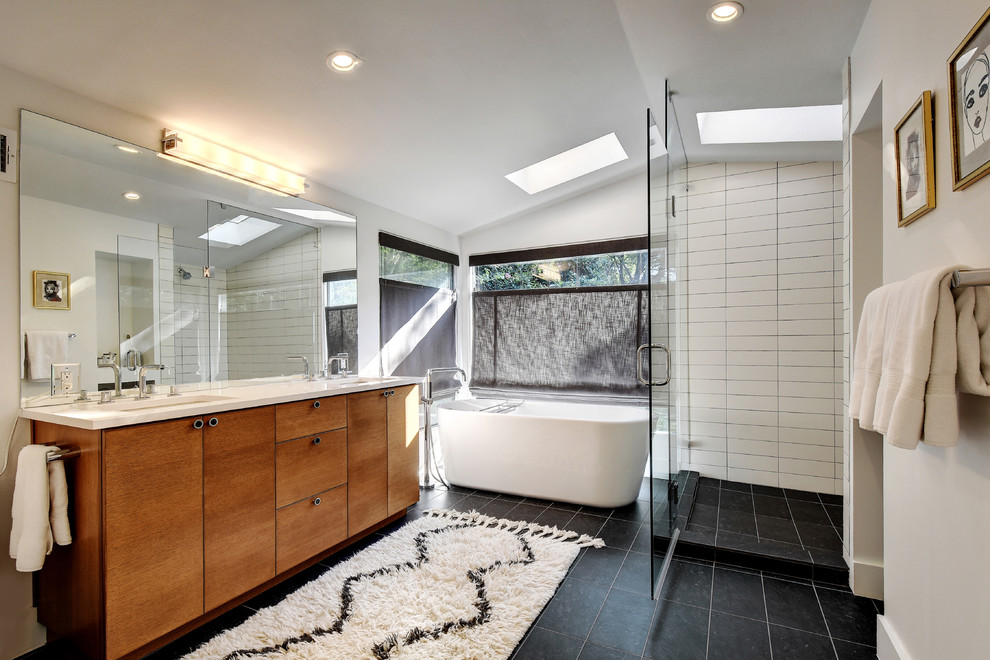 Inspiration for a large contemporary master bathroom in Austin with an undermount sink, flat-panel cabinets, medium wood cabinets, engineered quartz benchtops, a freestanding tub, a corner shower, a one-piece toilet, black and white tile, stone tile, white walls, porcelain floors, black floor and a hinged shower door.