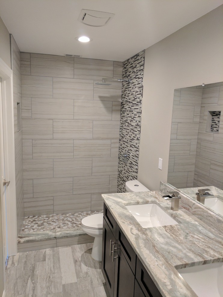 Example of a mid-sized transitional 3/4 gray tile and porcelain tile light wood floor and gray floor alcove shower design with shaker cabinets, dark wood cabinets, a two-piece toilet, gray walls, an undermount sink, granite countertops and gray countertops