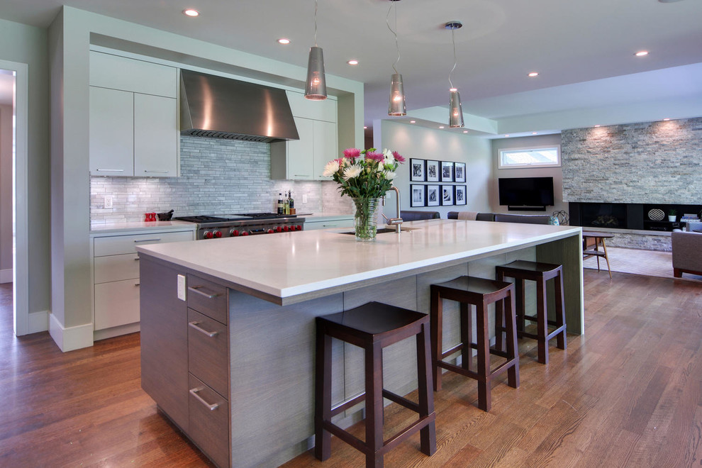 Inspiration for a transitional medium tone wood floor and brown floor kitchen remodel in Calgary with an undermount sink, flat-panel cabinets, quartz countertops, gray backsplash, marble backsplash, stainless steel appliances and an island