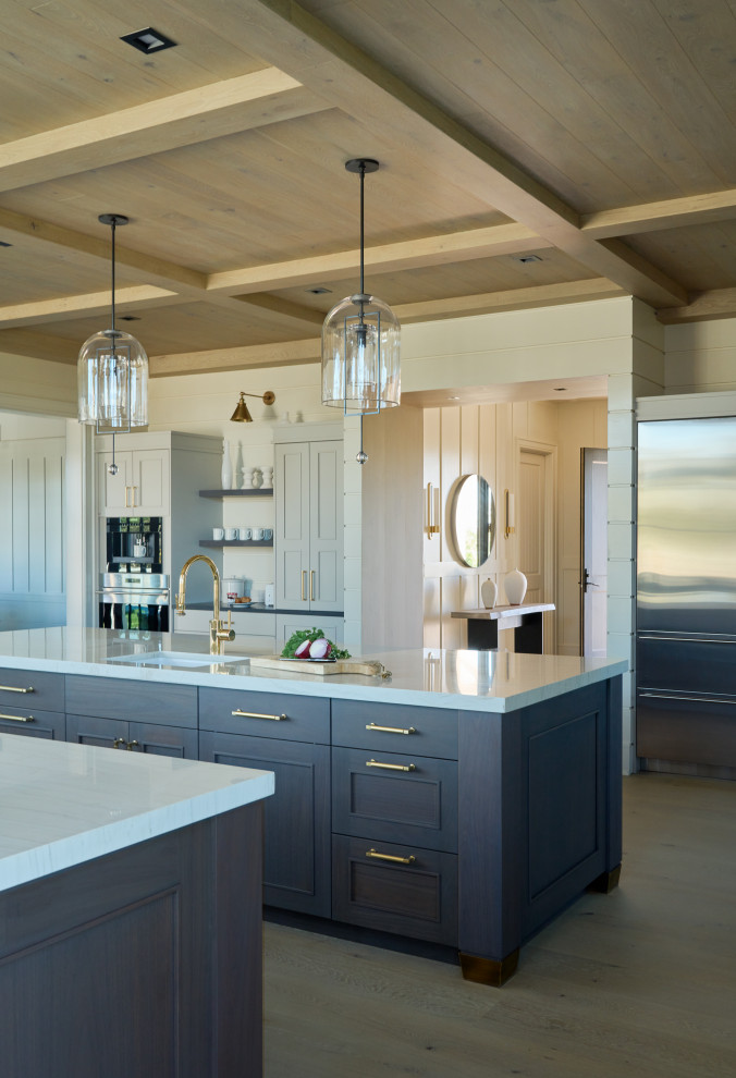 Industrial u-shaped open plan kitchen in New York with a farmhouse sink, recessed-panel cabinets, blue cabinets, quartz benchtops, white splashback, shiplap splashback, stainless steel appliances, light hardwood floors, multiple islands, beige floor, white benchtop and wood.