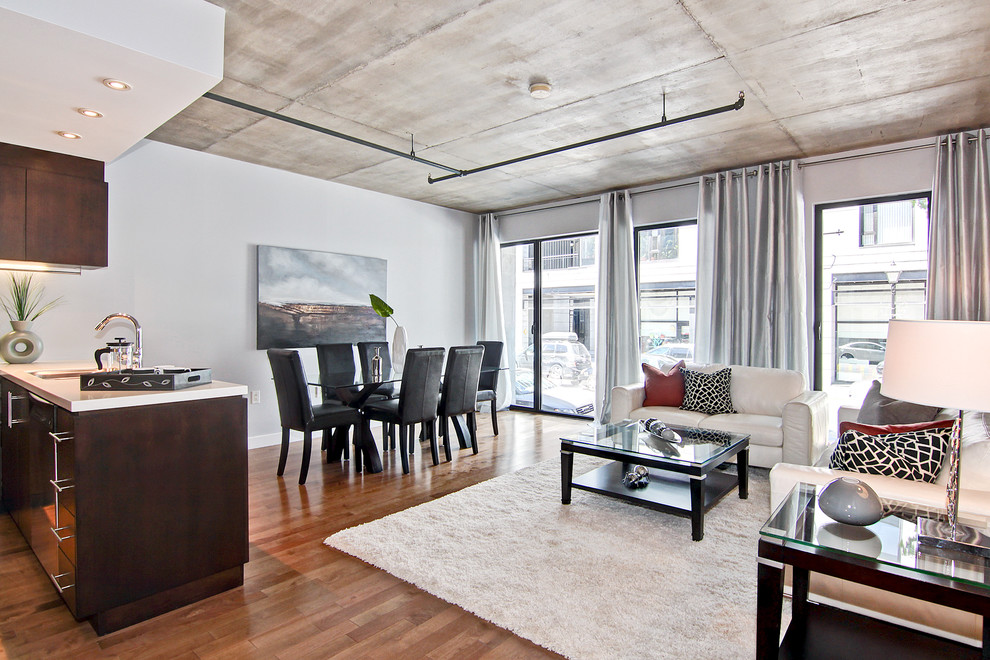 Example of a mid-sized urban open concept medium tone wood floor living room design in Montreal with gray walls