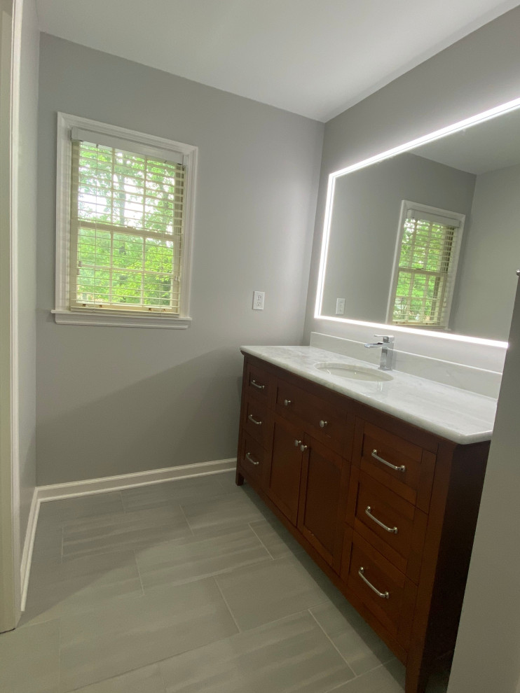 Inspiration for a mid-sized transitional master white tile porcelain tile, gray floor and double-sink alcove bathtub remodel with recessed-panel cabinets, light wood cabinets, a two-piece toilet, an undermount sink, granite countertops, white countertops and a freestanding vanity