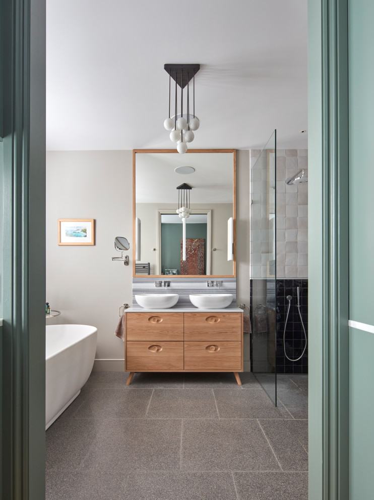 This is an example of a large contemporary master bathroom in London with light wood cabinets, a freestanding tub, an open shower, black and white tile, cement tile, terrazzo floors, a vessel sink, marble benchtops, an open shower, multi-coloured benchtops, grey walls, grey floor and flat-panel cabinets.