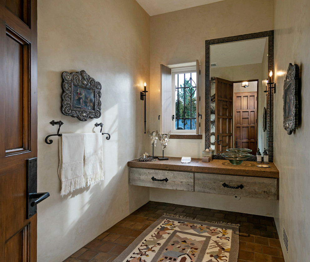 This is an example of a mid-sized mediterranean powder room in Santa Barbara with beige walls, terra-cotta floors and brown floor.