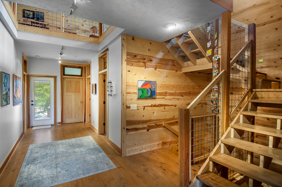 Inspiration for a mid-sized farmhouse medium tone wood floor hallway remodel in Omaha with white walls