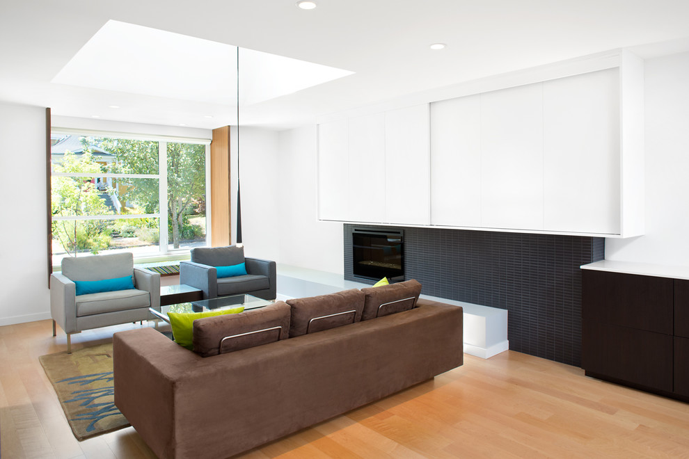 This is an example of a contemporary formal enclosed living room in Vancouver with white walls, light hardwood floors, a standard fireplace, a tile fireplace surround and no tv.