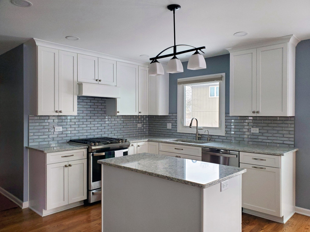 Medium sized classic u-shaped open plan kitchen in Chicago with a submerged sink, shaker cabinets, white cabinets, engineered stone countertops, blue splashback, glass tiled splashback, stainless steel appliances, medium hardwood flooring, an island, brown floors and grey worktops.