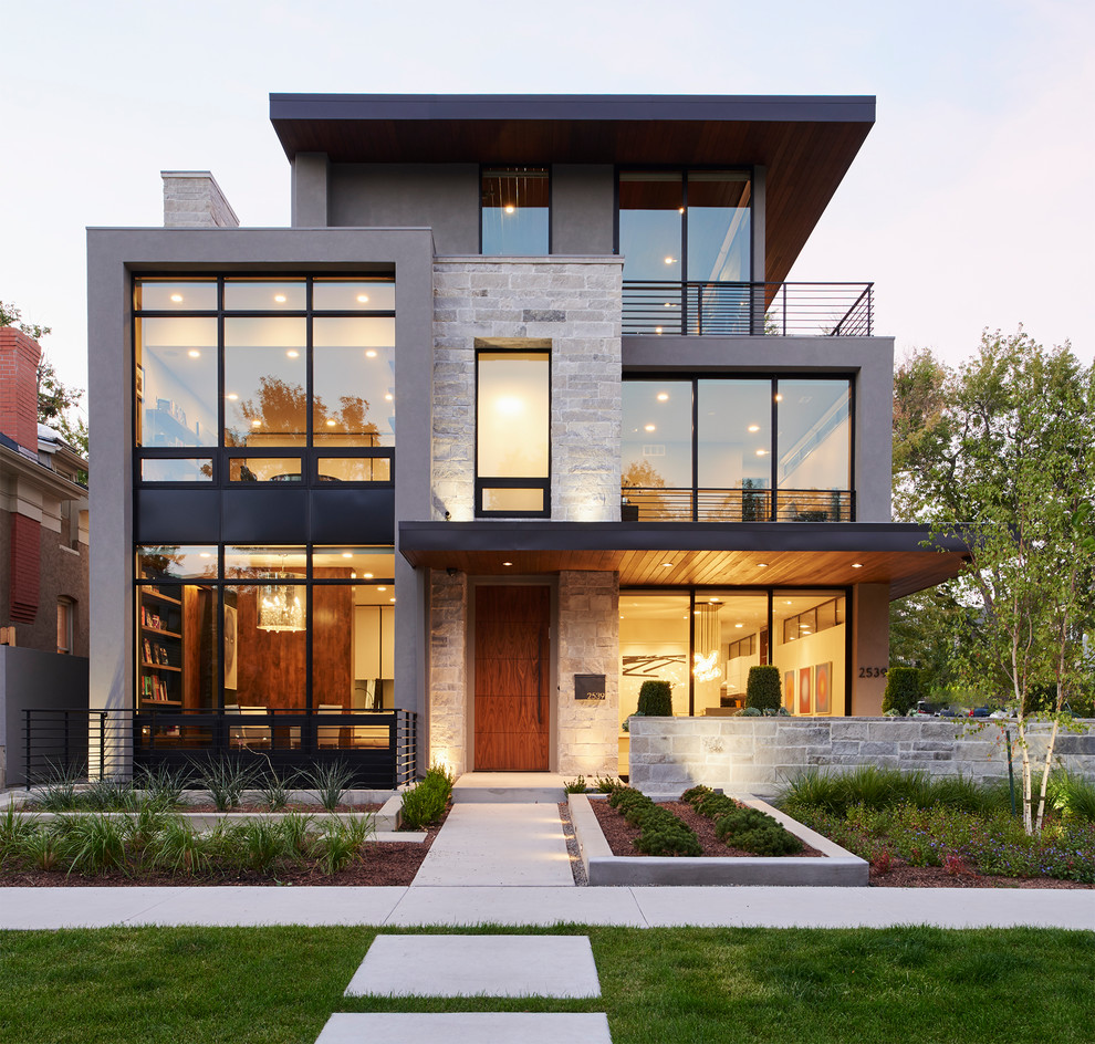 Photo of a mid-sized modern three-storey grey house exterior in Denver with stone veneer and a flat roof.