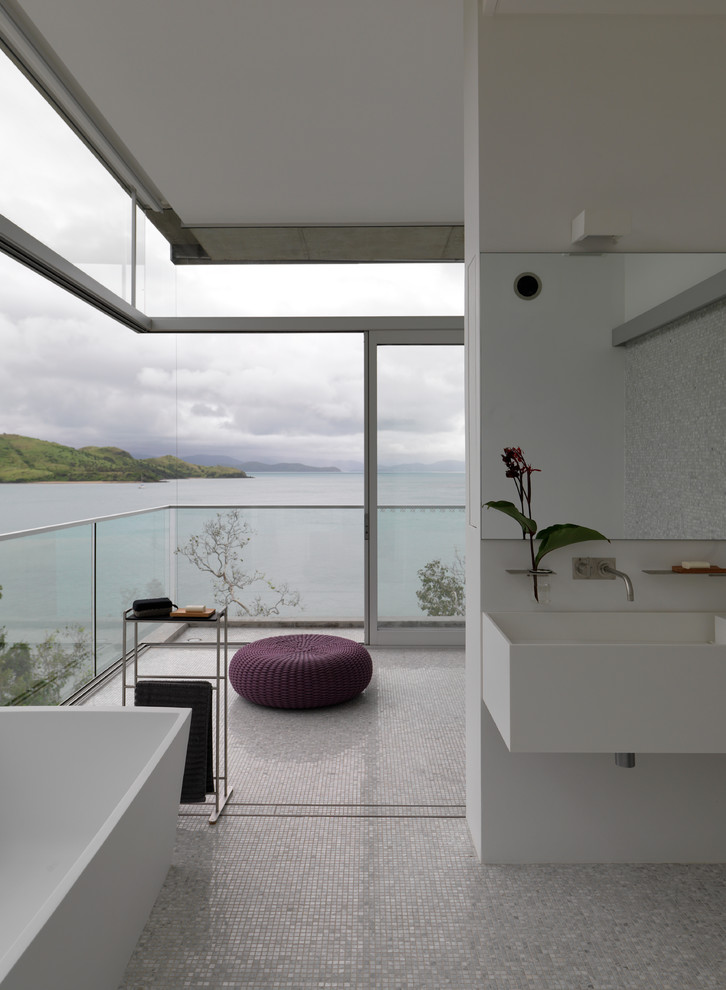 Inspiration for a beach style master bathroom in Townsville with a freestanding tub, an open shower, a wall-mount toilet, stone tile, white walls, a wall-mount sink, white floor and an open shower.