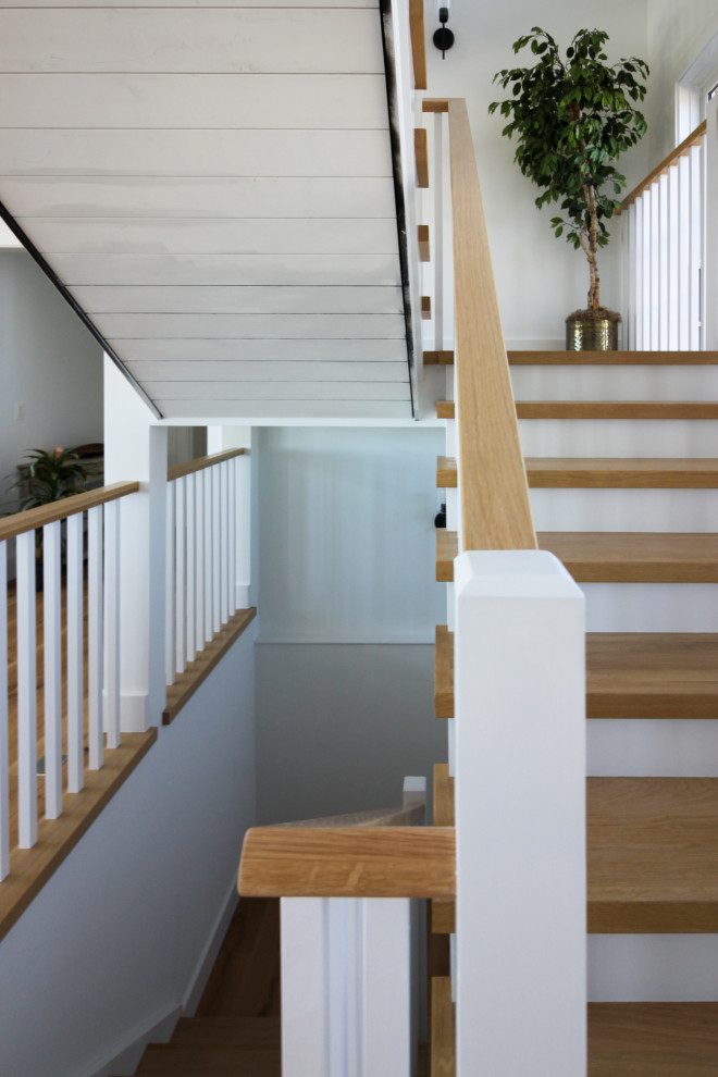 Diseño de escalera en U de estilo de casa de campo de tamaño medio con escalones de madera, contrahuellas de madera, barandilla de madera y machihembrado