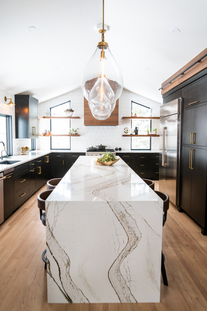This is an example of a midcentury kitchen in Other with an undermount sink, flat-panel cabinets, black cabinets, quartz benchtops, white splashback, ceramic splashback, stainless steel appliances, light hardwood floors, with island, multi-coloured benchtop and vaulted.