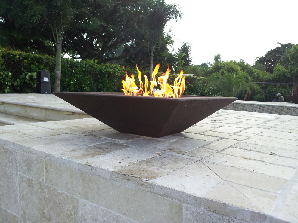 Photo of a modern backyard patio in Miami with a fire feature and natural stone pavers.