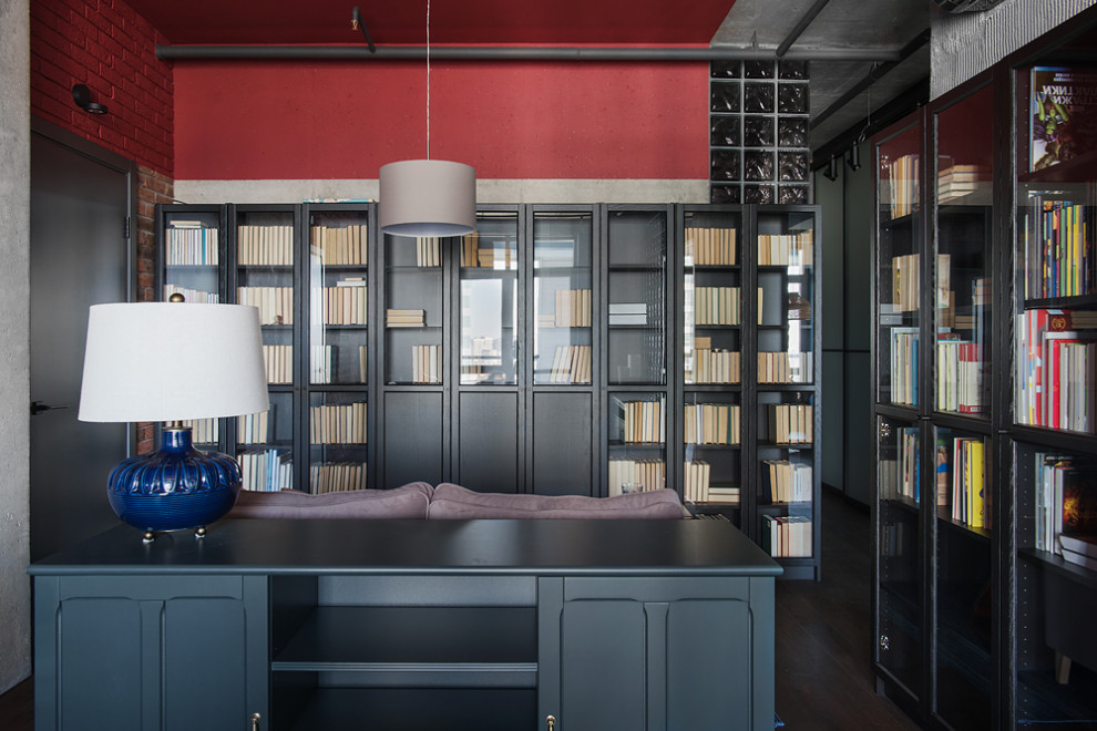 Inspiration för ett mellanstort industriellt hemmabibliotek, med röda väggar, mörkt trägolv, ett fristående skrivbord och brunt golv