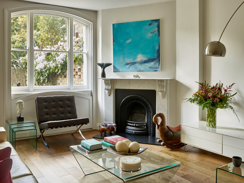 Photo of an eclectic open concept living room in London with white walls, medium hardwood floors, a standard fireplace, a stone fireplace surround, no tv and brown floor.