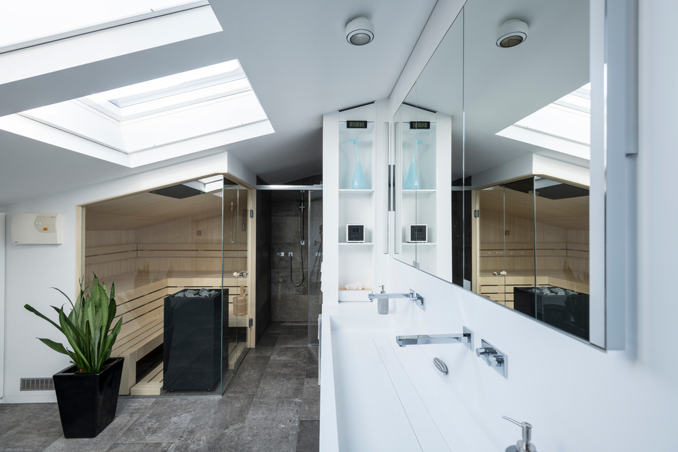 This is an example of a mid-sized contemporary bathroom in Nuremberg with an alcove shower, gray tile, white walls, with a sauna, a trough sink, grey floor, white benchtops and a hinged shower door.