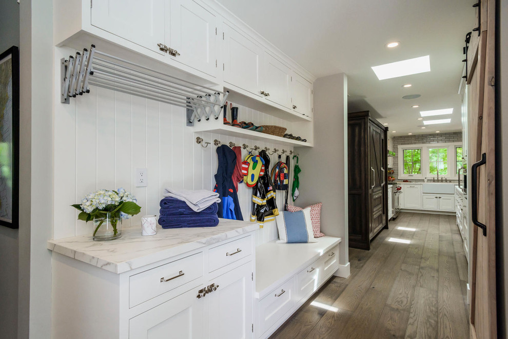 Large transitional galley utility room in San Francisco with a farmhouse sink, shaker cabinets, white cabinets, grey walls, dark hardwood floors and a stacked washer and dryer.