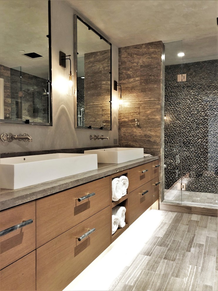 Inspiration for a large contemporary master bathroom in Denver with flat-panel cabinets, medium wood cabinets, an alcove shower, a two-piece toilet, stone tile, multi-coloured walls, porcelain floors, a vessel sink, concrete benchtops, grey floor, a hinged shower door and grey benchtops.