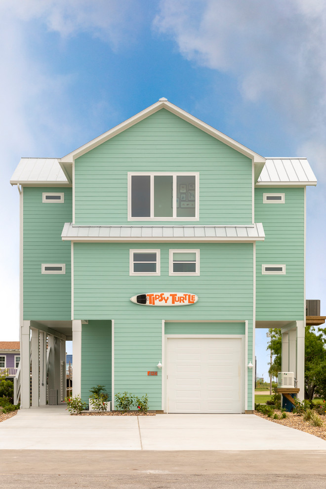 Inspiration for a large beach style two-storey blue house exterior with vinyl siding, a hip roof and a metal roof.