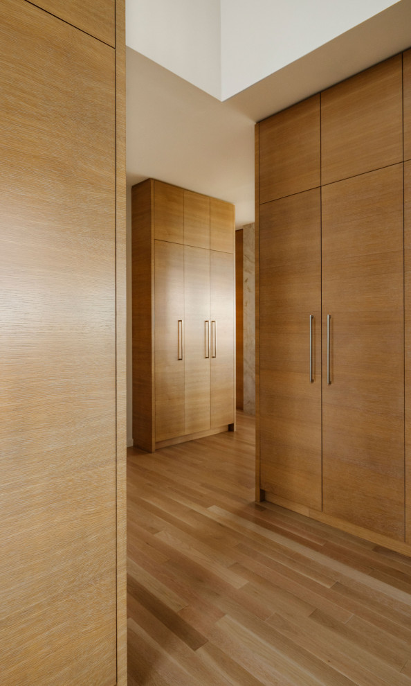 This is an example of a large contemporary entryway in Calgary with light hardwood floors, beige floor and wood walls.