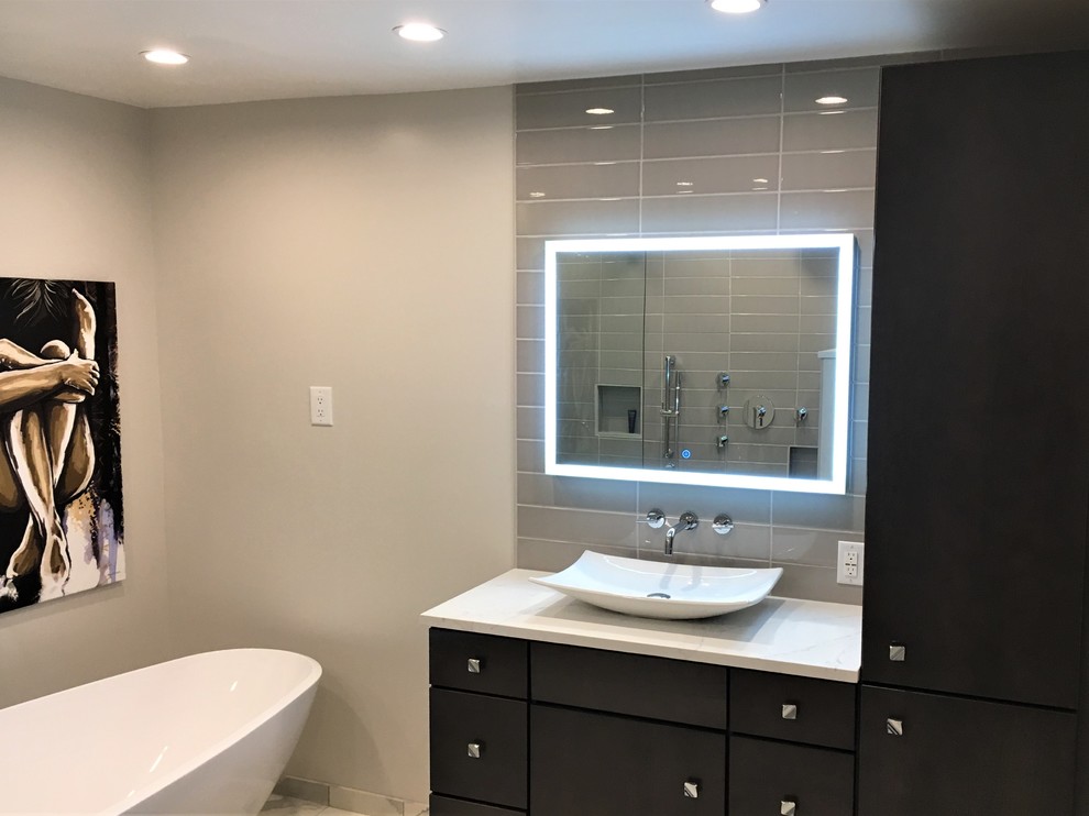 This is an example of a mid-sized modern master wet room bathroom in Other with flat-panel cabinets, brown cabinets, a freestanding tub, a two-piece toilet, gray tile, ceramic tile, grey walls, porcelain floors, a vessel sink, engineered quartz benchtops, multi-coloured floor, an open shower, white benchtops, a single vanity and a built-in vanity.