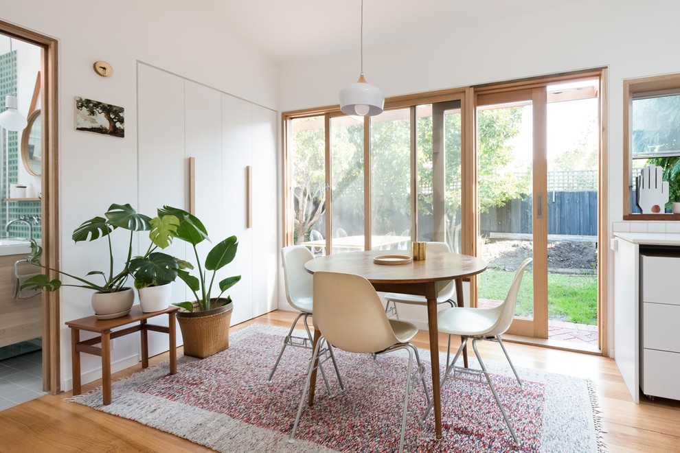 This is an example of a small scandinavian kitchen/dining combo in Melbourne with white walls, light hardwood floors and brown floor.