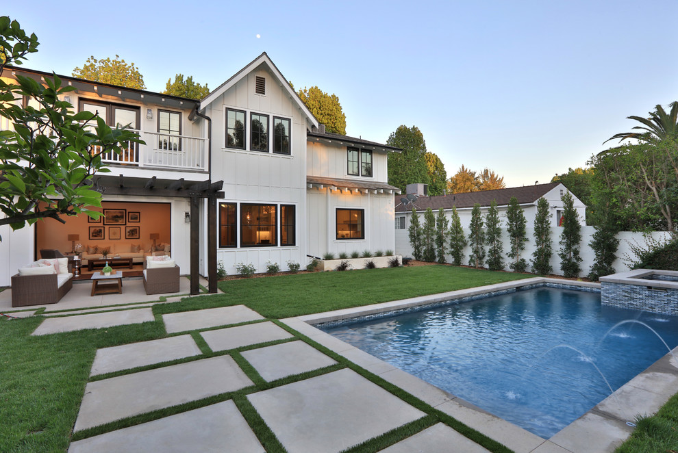 This is an example of a mid-sized country backyard rectangular pool in Los Angeles with a hot tub and concrete pavers.