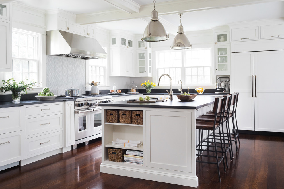 This is an example of a beach style l-shaped kitchen in Portland Maine with shaker cabinets, white cabinets, grey splashback, stainless steel appliances, dark hardwood floors and with island.