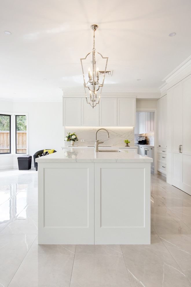 Inspiration for a large traditional l-shaped open plan kitchen in Sydney with an undermount sink, shaker cabinets, beige cabinets, quartz benchtops, grey splashback, stone slab splashback, stainless steel appliances, porcelain floors, with island, brown floor and white benchtop.